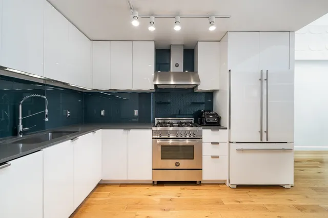 a kitchen with stainless steel appliances granite countertop a stove a sink and a refrigerator