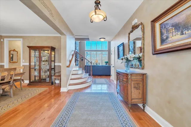 a kitchen with stainless steel appliances granite countertop a refrigerator a sink a stove a dining table and chairs with wooden floor