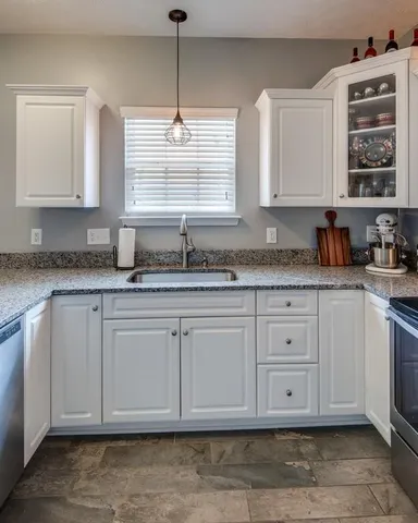 a kitchen with granite countertop white cabinets white appliances and a sink