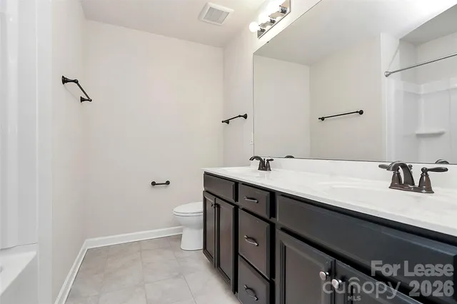 a bathroom with a granite countertop sink a toilet and a mirror