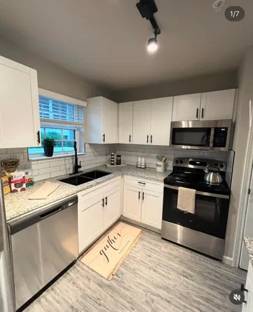a kitchen with granite countertop a sink cabinets and stainless steel appliances