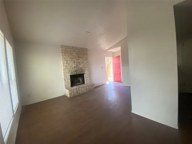 an empty room with windows and fireplace