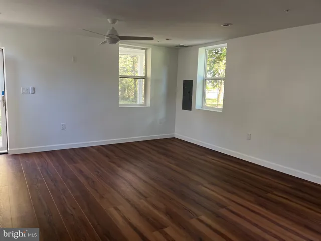an empty room with wooden floor and windows
