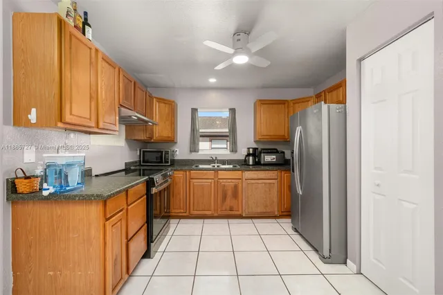 a kitchen with stainless steel appliances granite countertop a refrigerator a sink dishwasher a stove with wooden cabinets and a refrigerator