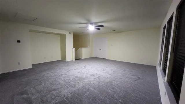 an empty room with a ceiling fan and window