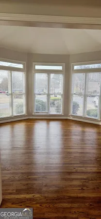 a view of empty room with wooden floor and floor to ceiling window