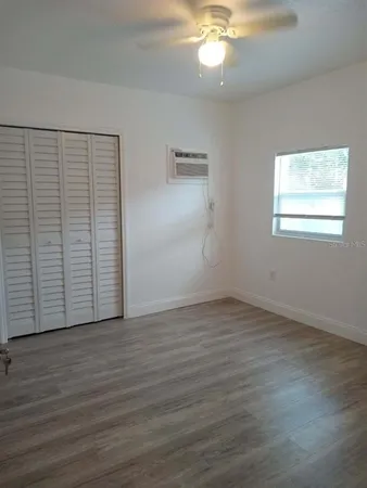 an empty room with wooden floor chandelier fan and windows