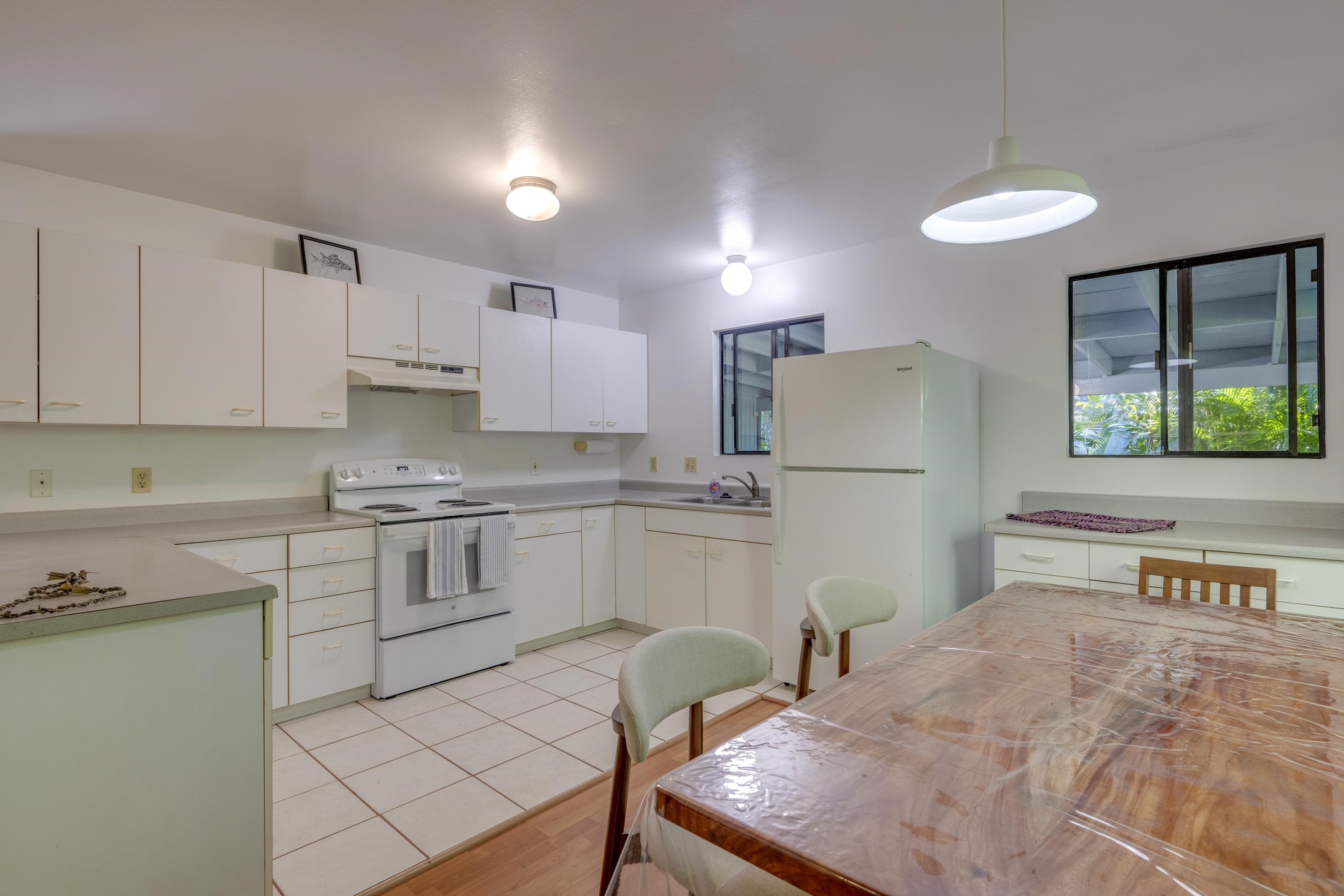 1002 Kauhikoa Road, Unit 2 Haiku, HI 96708 - Photo 15 of 24 a kitchen with stainless steel appliances granite countertop a refrigerator a stove a sink dishwasher and white cabinets with wooden floor