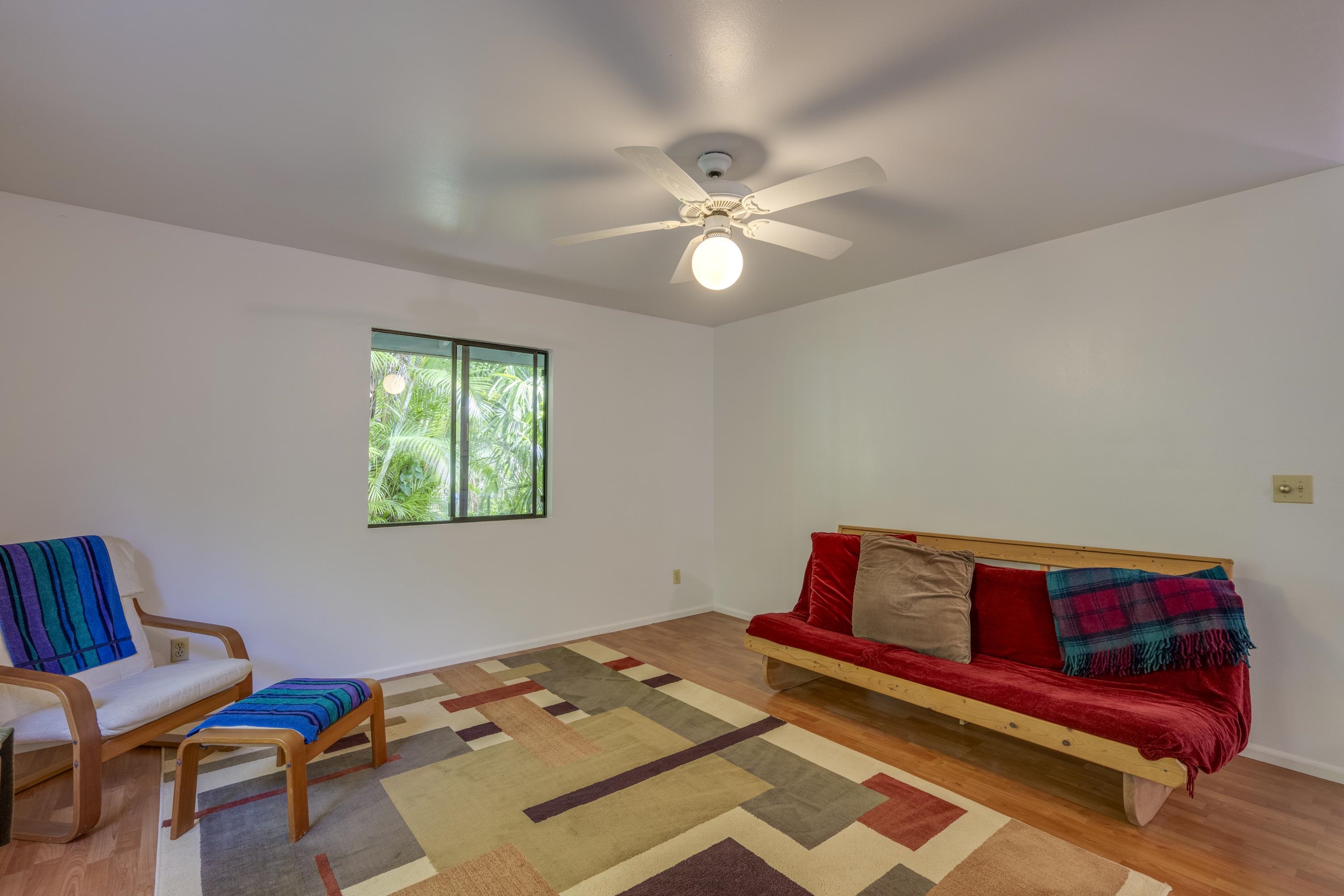 1002 Kauhikoa Road, Unit 2 Haiku, HI 96708 - Photo 10 of 24 a bedroom with a bed and a chandelier