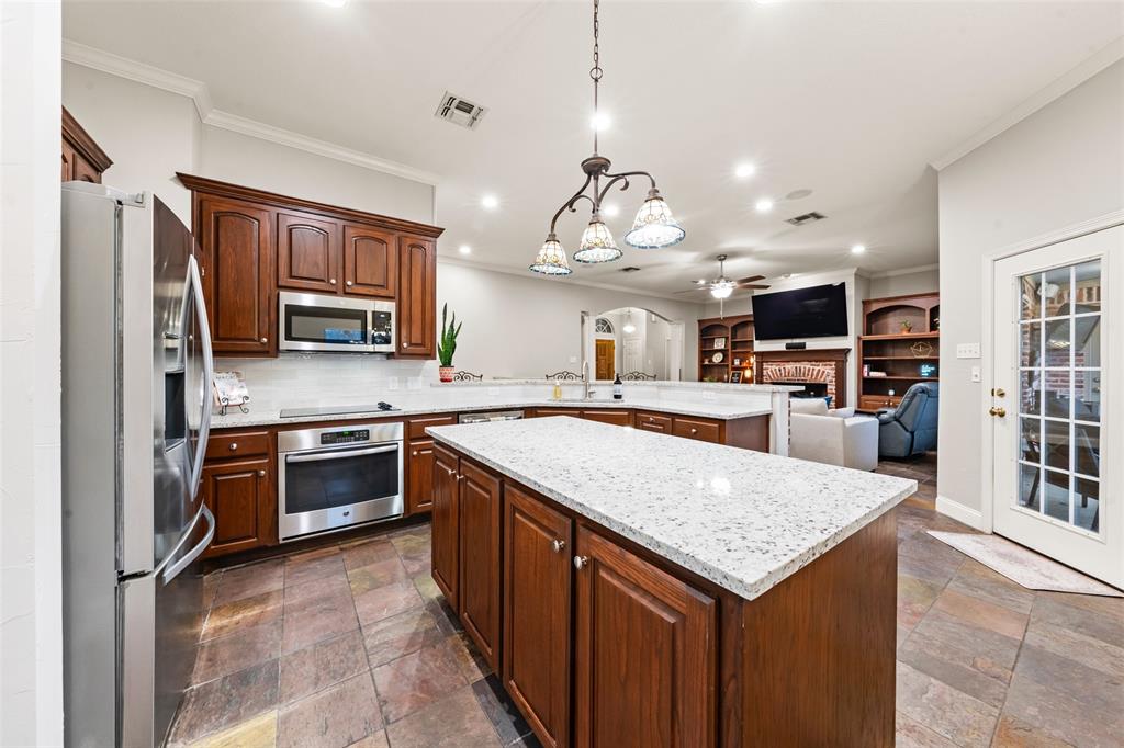 517 Chado Lane Robinson, TX 76706 - Photo 40 of 40 Kitchen with arched walkways, stainless steel appliances, a peninsula, ornamental molding, and open floor plan