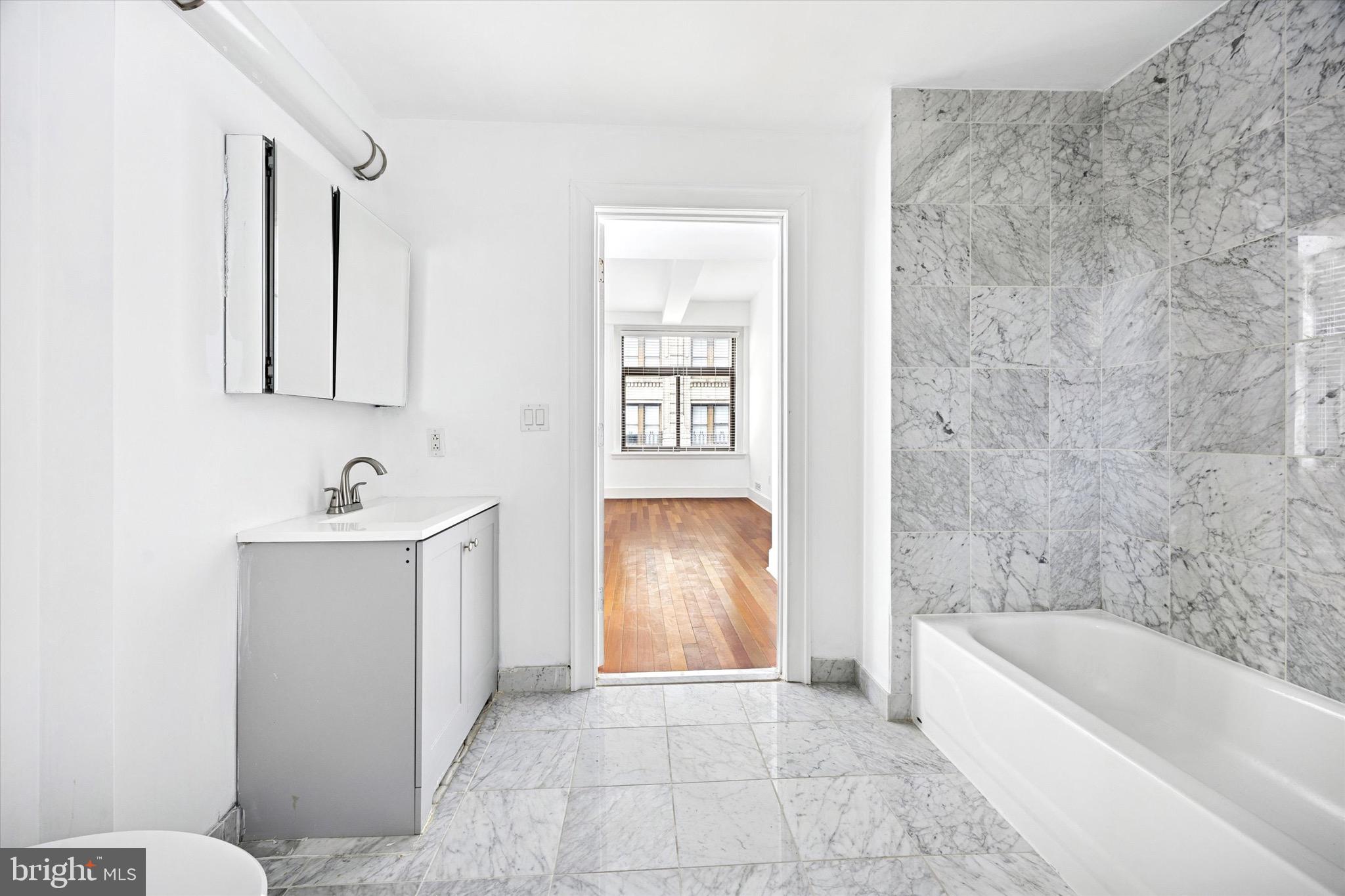 1500 Chestnut Street, Unit 15H Philadelphia, PA 19102 - Photo 19 of 25 a bathroom with a bathtub sink vanity and mirror
