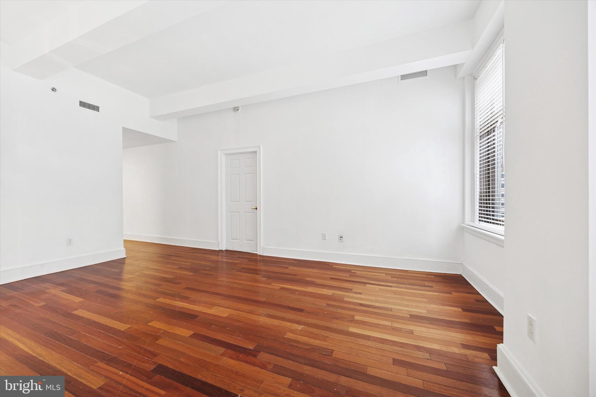 1500 Chestnut Street, Unit 15H Philadelphia, PA 19102 - Photo 10 of 25 a view of an empty room with wooden floor and a window