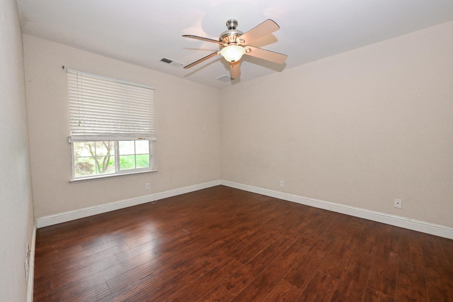 21088 Forest Glen Road Madera, CA 93638 - Photo 15 of 31 an empty room with wooden floor chandelier fan and windows