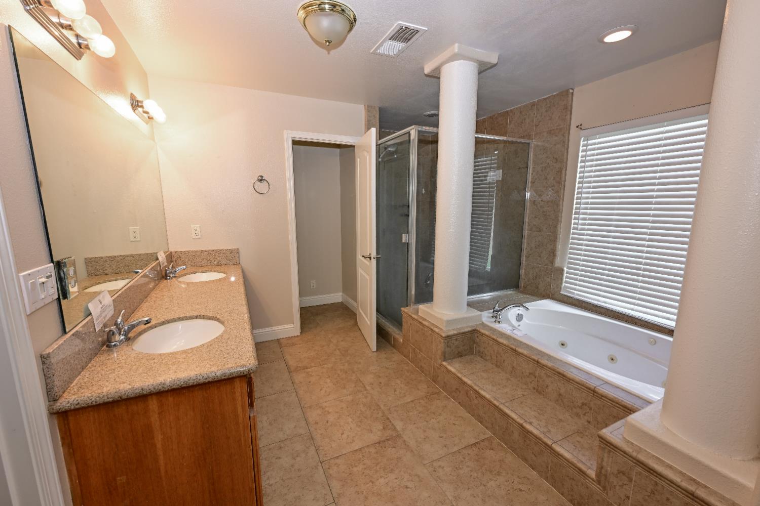 21088 Forest Glen Road Madera, CA 93638 - Photo 20 of 31 a bathroom with a double vanity sink large mirror and a bathtub