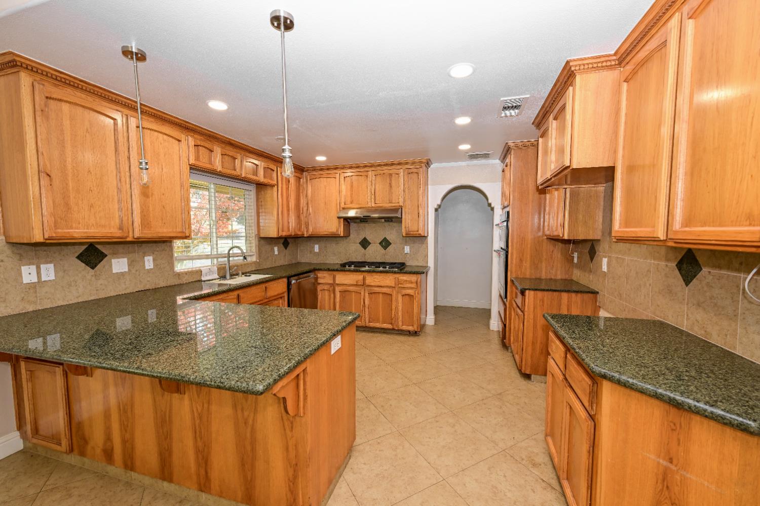 21088 Forest Glen Road Madera, CA 93638 - Photo 7 of 31 a kitchen with stainless steel appliances granite countertop a sink a stove and a wooden cabinets