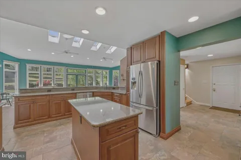 a kitchen with stainless steel appliances granite countertop a refrigerator a sink dishwasher and wooden cabinets with a granite countertops