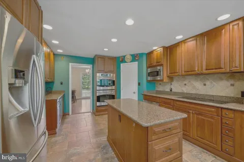 a kitchen with stainless steel appliances granite countertop a refrigerator a sink dishwasher and wooden cabinets with a granite countertops