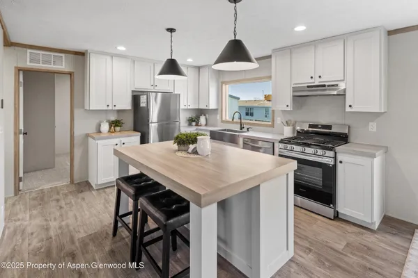 a kitchen with stainless steel appliances a stove a sink a refrigerator and a center island