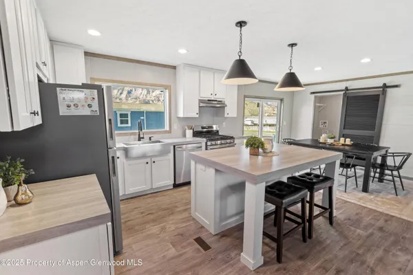 a kitchen with stainless steel appliances granite countertop a sink a stove a dining table and chairs