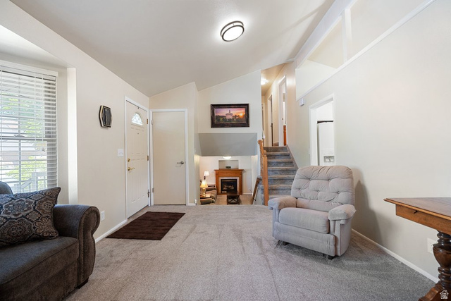 865 South 325 West Orem, UT 84058 - Photo 8 of 38 Inviting living space featuring vaulted ceilings, a prominent entry door with an arched window, and a lower-level fireplace