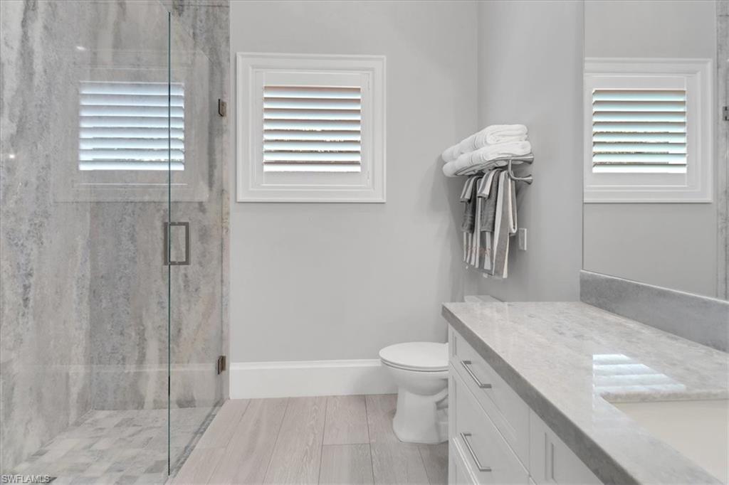 1425 Crayton Road Naples, FL 34102 - Photo 18 of 31 Bathroom featuring a shower with shower door, vanity, and toilet