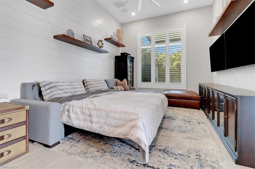 1425 Crayton Road Naples, FL 34102 - Photo 20 of 31 Bedroom with wood walls, light wood-type flooring, and ceiling fan
