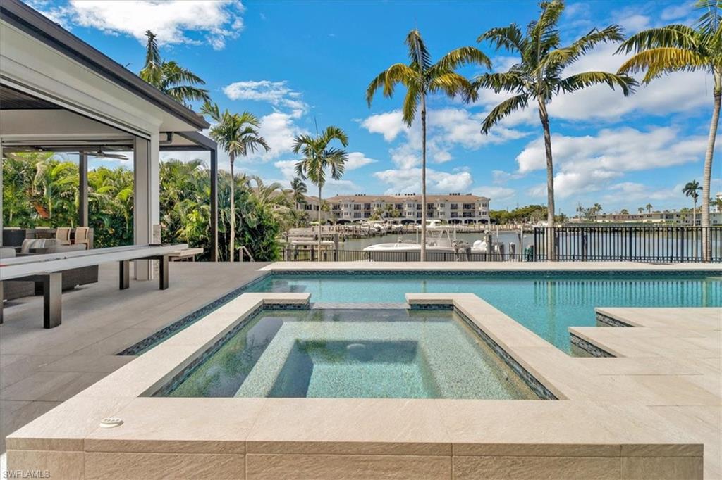 1425 Crayton Road Naples, FL 34102 - Photo 27 of 31 View of pool featuring a water view, an in ground hot tub, and a patio area