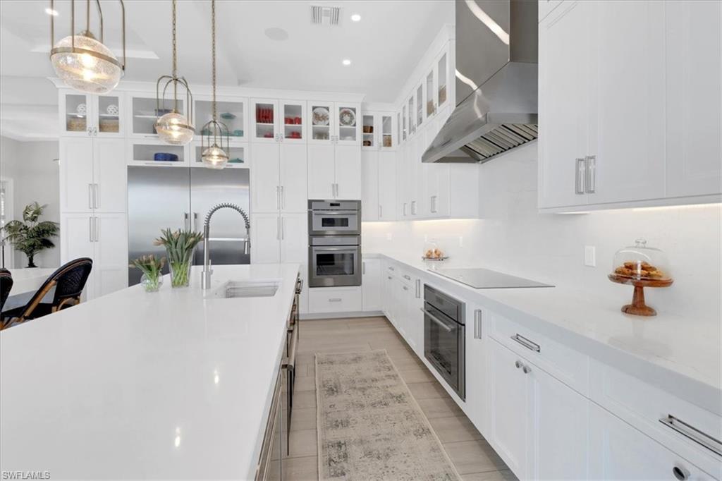 1425 Crayton Road Naples, FL 34102 - Photo 5 of 31 Kitchen featuring pendant lighting, appliances with stainless steel finishes, white cabinets, and wall chimney range hood