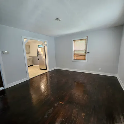 a view of an empty room with wooden floor and a window