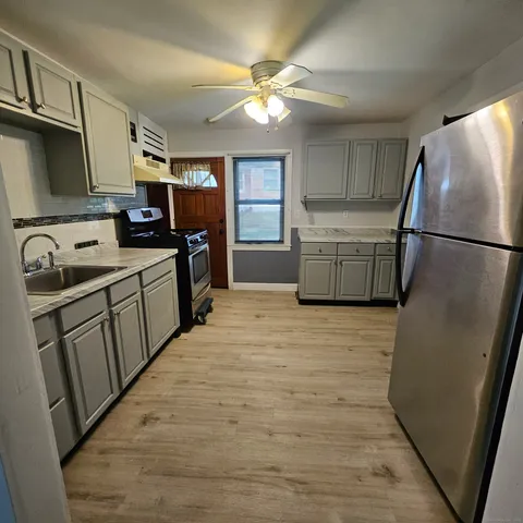 a kitchen with refrigerator a sink a stove and cabinets