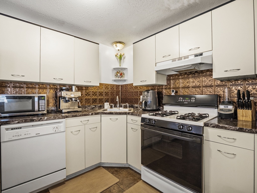 34 Newhall Street, Unit 412 Lowell, MA 01852 - Photo 7 of 30 a kitchen with granite countertop white cabinets and white appliances