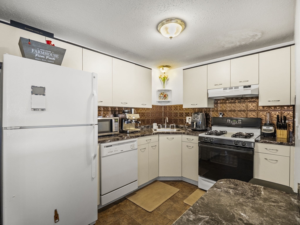 34 Newhall Street, Unit 412 Lowell, MA 01852 - Photo 8 of 30 a kitchen with a sink a stove and refrigerator