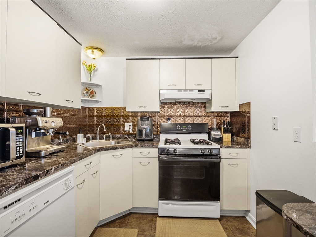 34 Newhall Street, Unit 412 Lowell, MA 01852 - Photo 9 of 30 a kitchen with a stove sink and cabinets