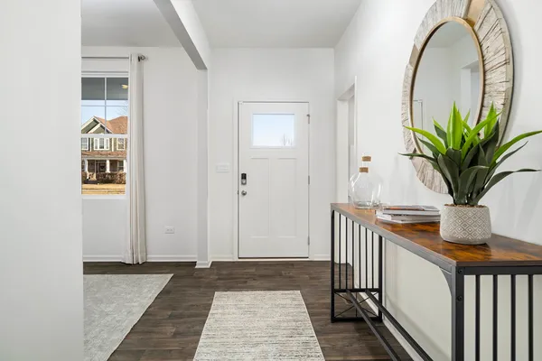 a kitchen with kitchen island granite countertop a dining table chairs and white cabinets with wooden floor