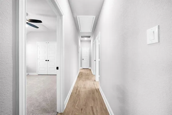 a view of empty room with wooden floor and fan