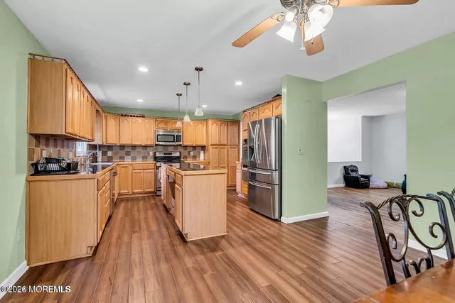 a kitchen with granite countertop a refrigerator a stove top oven a sink and dishwasher with wooden floor