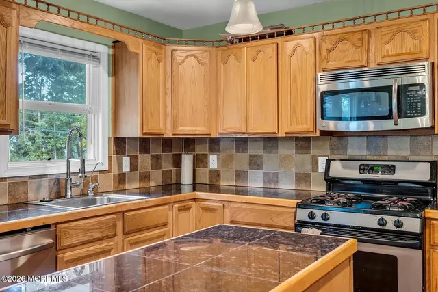 a kitchen with stainless steel appliances granite countertop a stove a sink and a microwave