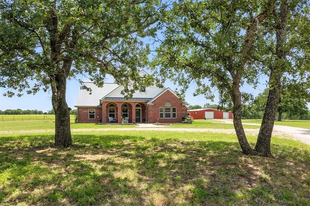 a front view of a house with a yard and large trees