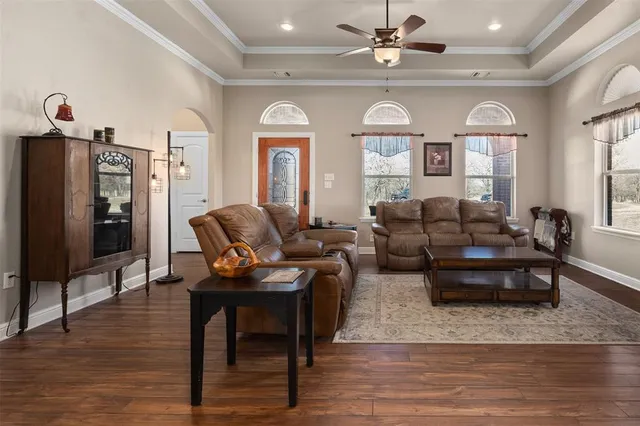 a living room with furniture a large window and wooden floor