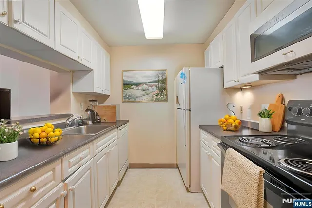 a kitchen with stainless steel appliances a stove a refrigerator and a white cabinets