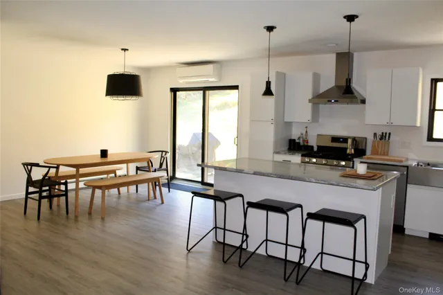 a kitchen with stainless steel appliances granite countertop a stove top oven a sink a dining table and chairs with wooden floor