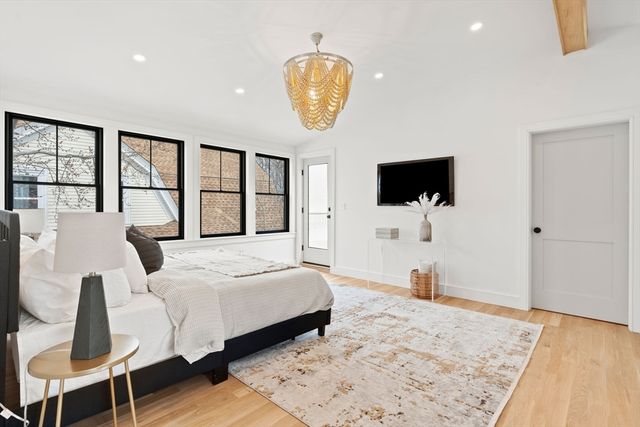 a bedroom with a bed a flat tv screen and a dresser