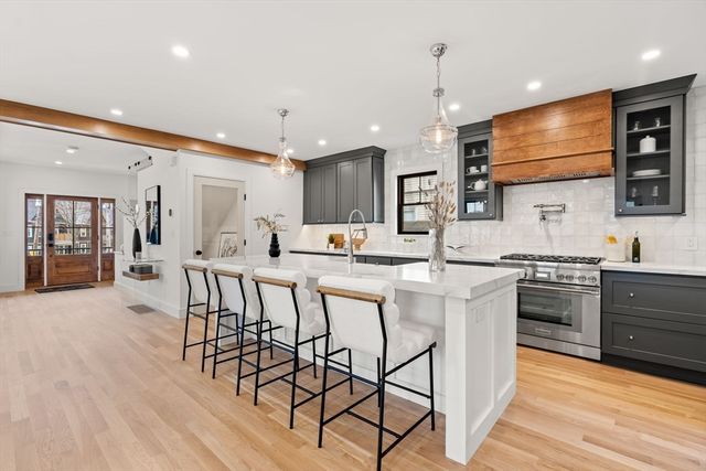 a open kitchen with stainless steel appliances granite countertop a stove top oven a sink dishwasher a dining table and chairs with wooden floor