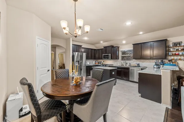 a open kitchen with stainless steel appliances kitchen island granite countertop a sink a stove a dining table and chairs