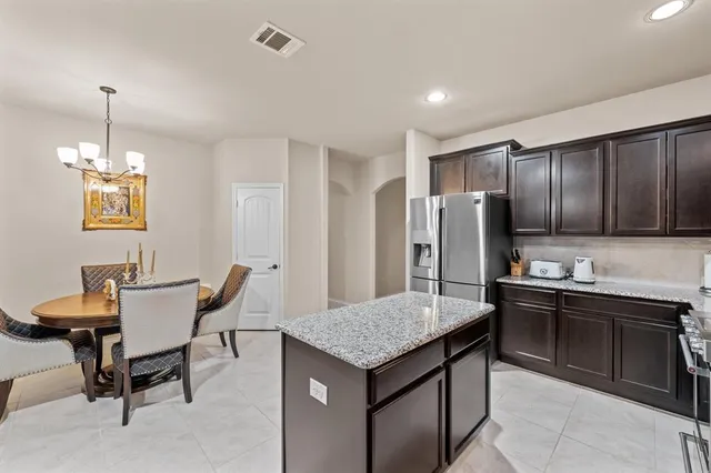 a kitchen that has a kitchen island wooden cabinets and stainless steel appliances