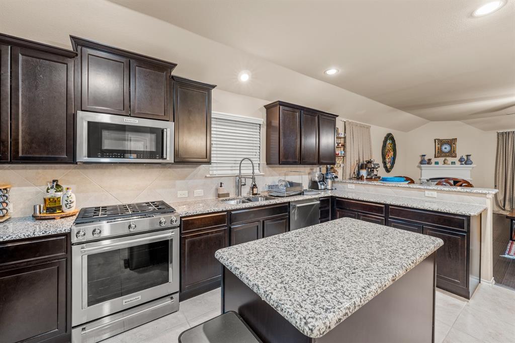 201 Whitman Drive McKinney, TX 75072 - Photo 31 of 33 a kitchen with stainless steel appliances granite countertop wooden cabinets sink stove and microwave