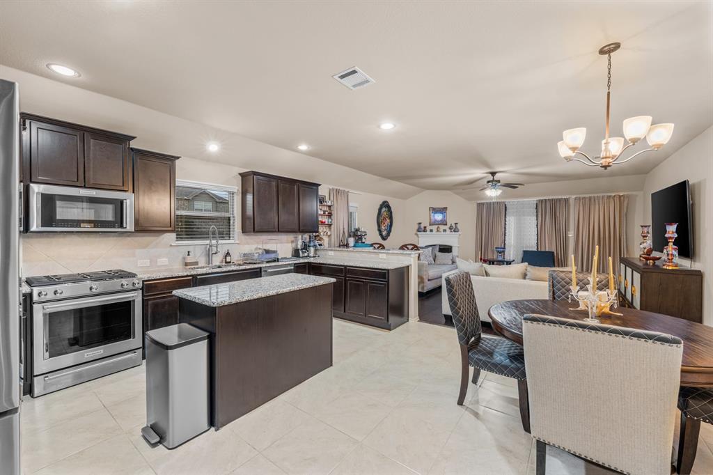 201 Whitman Drive McKinney, TX 75072 - Photo 10 of 33 a kitchen with stainless steel appliances granite countertop a stove top oven a sink dishwasher a dining table and chairs with wooden floor