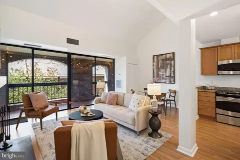a living room with furniture large windows and wooden floor