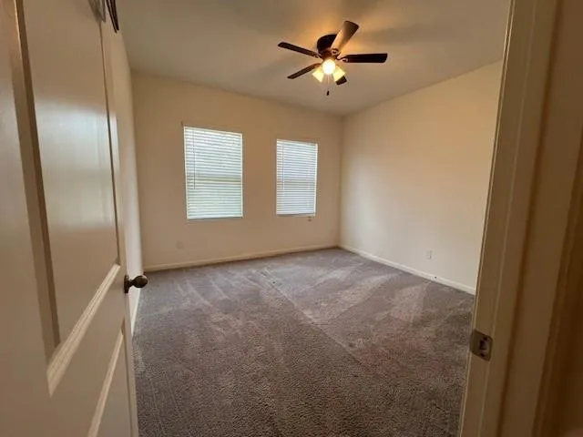 an empty room with windows and fan