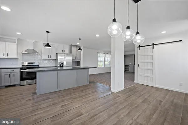 a large kitchen with white cabinets stainless steel appliances and wooden floor